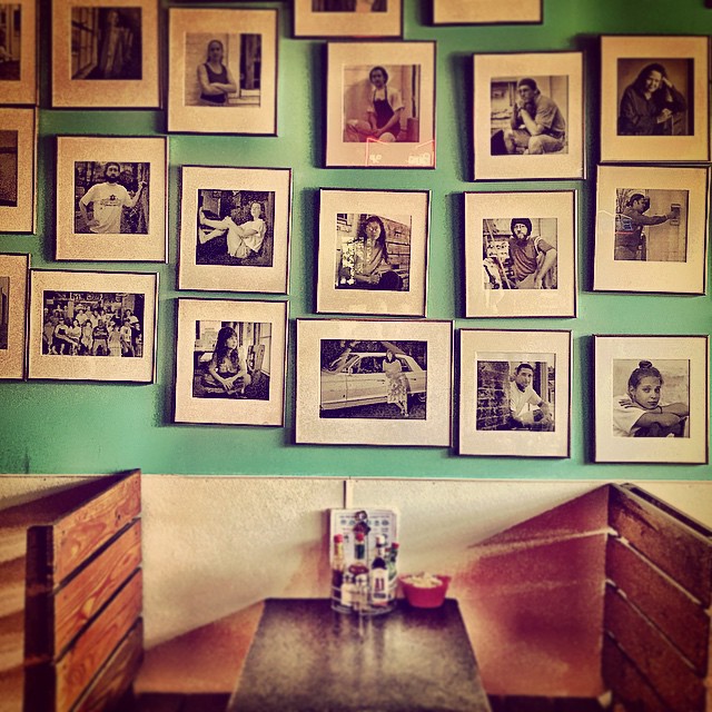 A wall of framed black and white portraits of regulars above a corner booth.